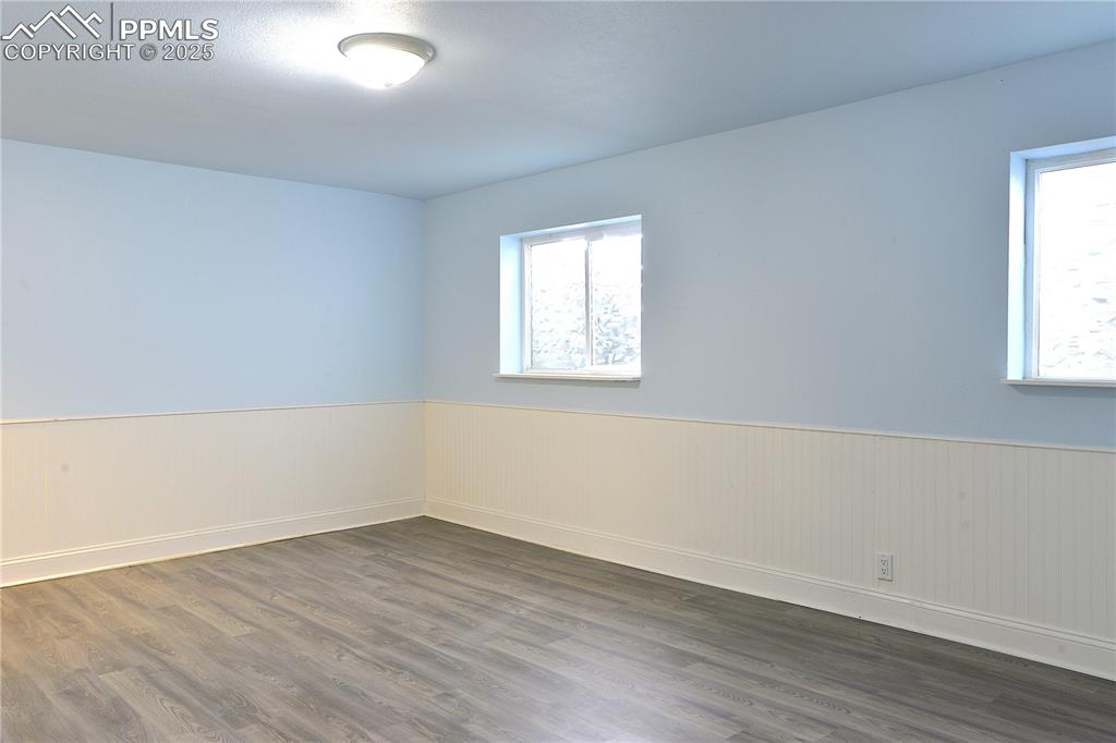 Image 19 of 29: Basement Family Room featuring wainscoting and solid surface flooring
