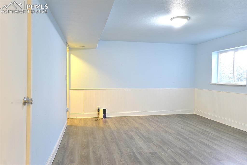 Image 21 of 29: Basement Family Room featuring wainscoting and solid surface flooring