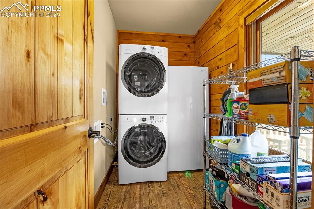 Image 12 of 45: Laundry room with stacked washing machine and dryer, wood finished floors,