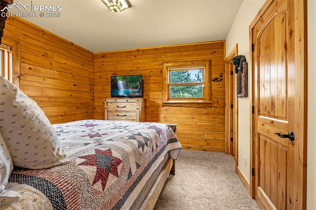Image 16 of 45: Carpeted bedroom with wooden walls