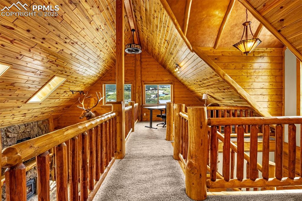 Image 19 of 45: Hallway featuring light colored carpet, wood ceiling, an upstairs landing,