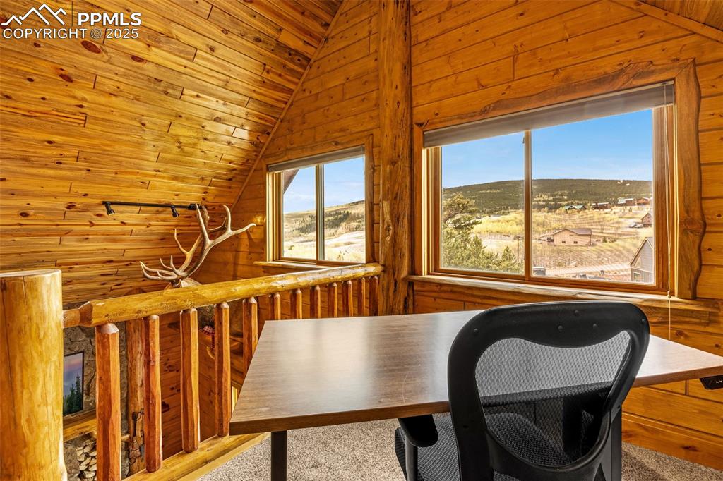Image 20 of 45: Home office featuring vaulted ceiling, wood walls, and carpet flooring