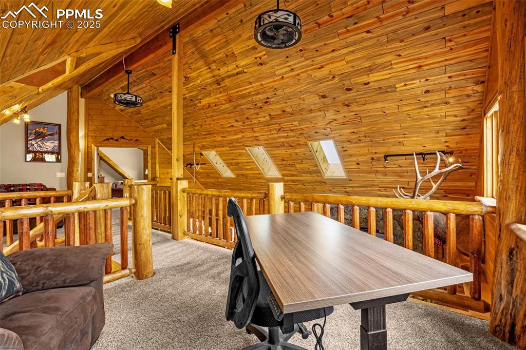 Image 21 of 45: Carpeted dining room with wooden walls, wooden ceiling, a skylight, and lof