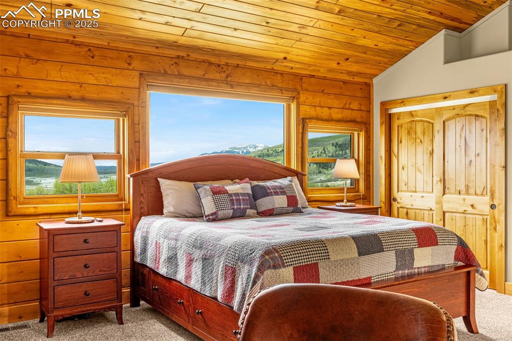 Image 25 of 45: Bedroom featuring light carpet, wood ceiling, multiple windows, vaulted cei