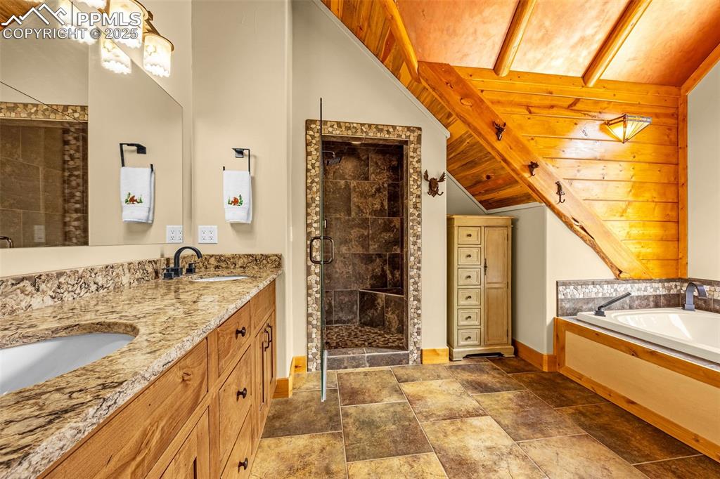 Image 26 of 45: Full bath with vaulted ceiling, a stall shower, baseboards, double vanity,