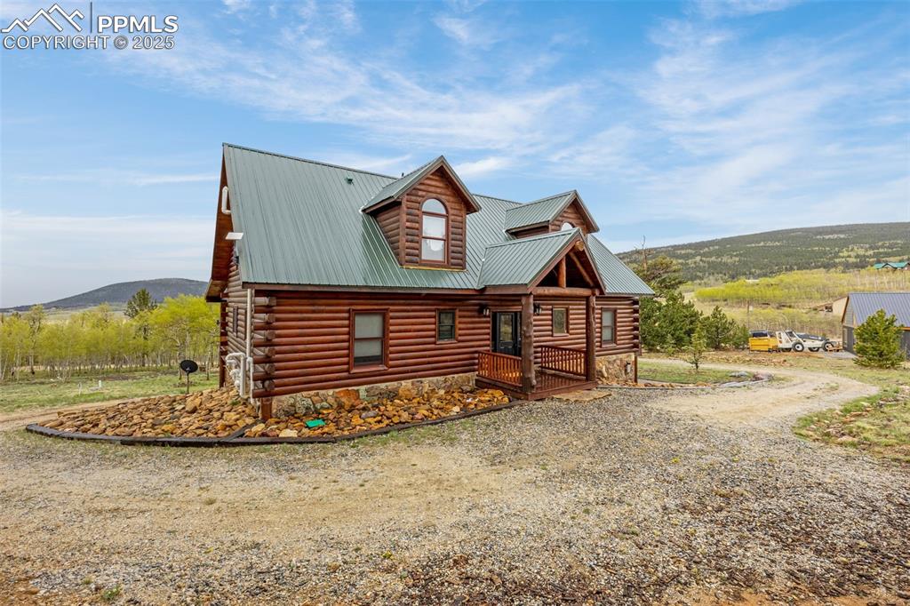 Image 3 of 45: View of front of property with metal roof, log siding, a mountain view, and