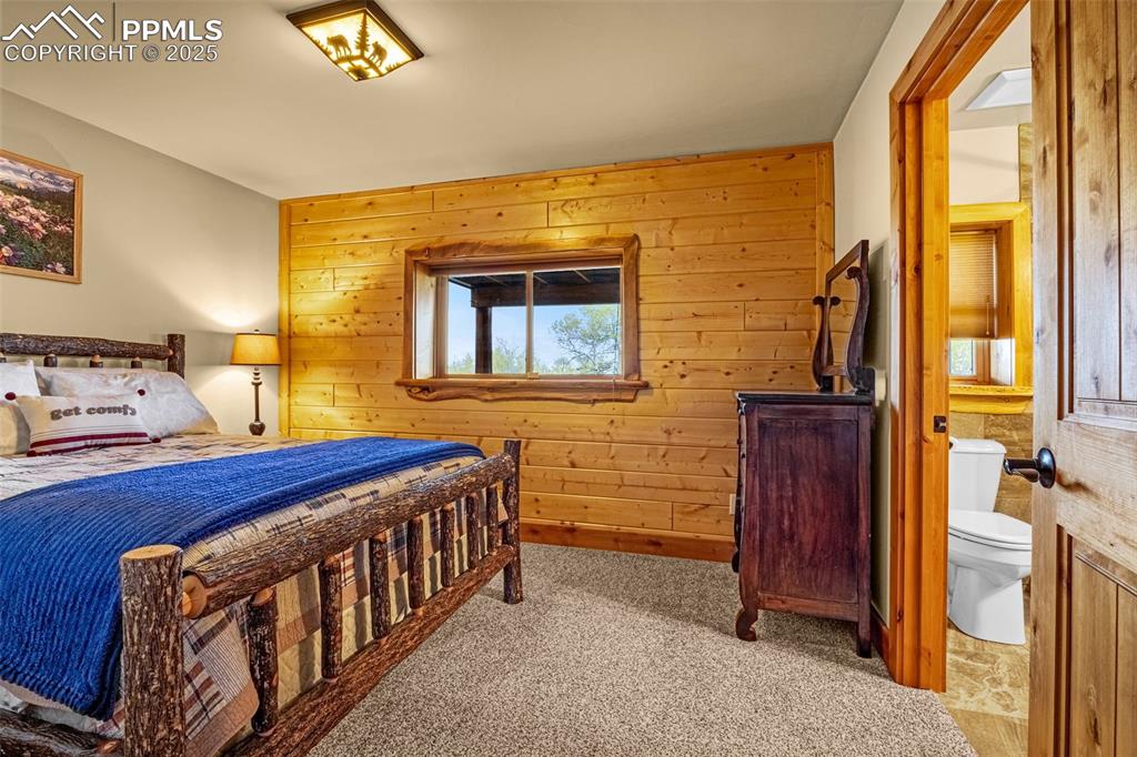 Image 34 of 45: Carpeted bedroom with wooden walls