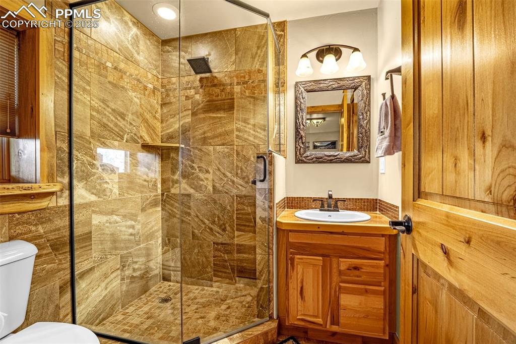 Image 35 of 45: Full bath with toilet, vanity, and a shower stall