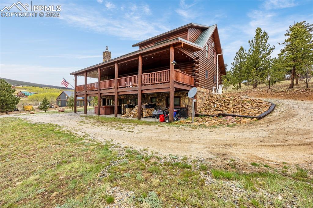 Image 39 of 45: Rear view of property featuring a deck, a chimney, driveway, and log siding