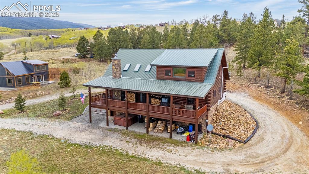 Image 41 of 45: Back of house with driveway, log siding, covered porch, and metal roof