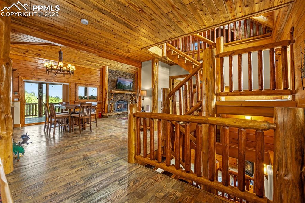 Image 5 of 45: Staircase with a chandelier, a stone fireplace, hardwood / wood-style floor