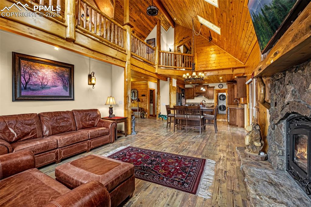Image 7 of 45: Living area with high vaulted ceiling, hardwood / wood-style floors, a chan