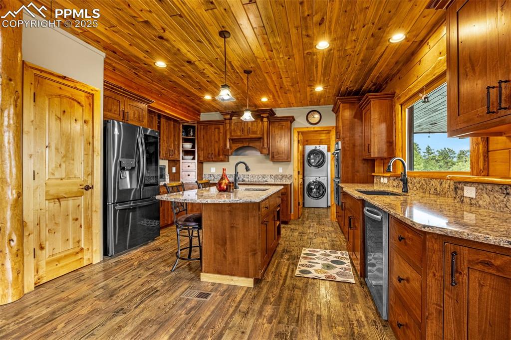 Image 8 of 45: Kitchen featuring fridge with ice dispenser, a sink, stacked washing machin