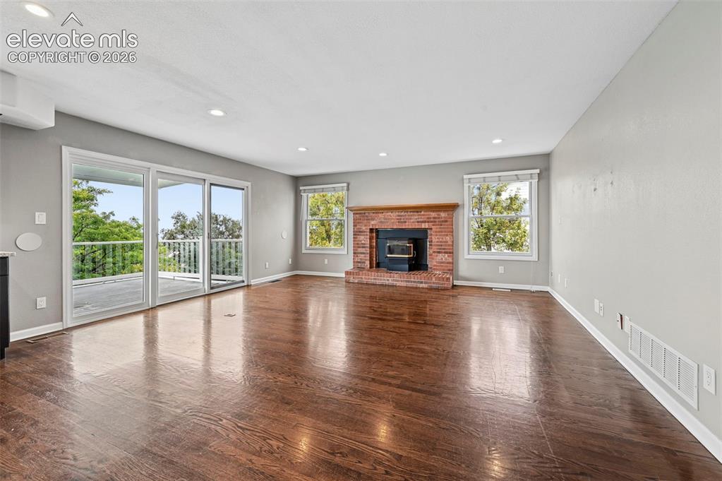 Image 12 of 45: Family room with brick fireplace/pellet stove, adjacent to kitchen - walkou