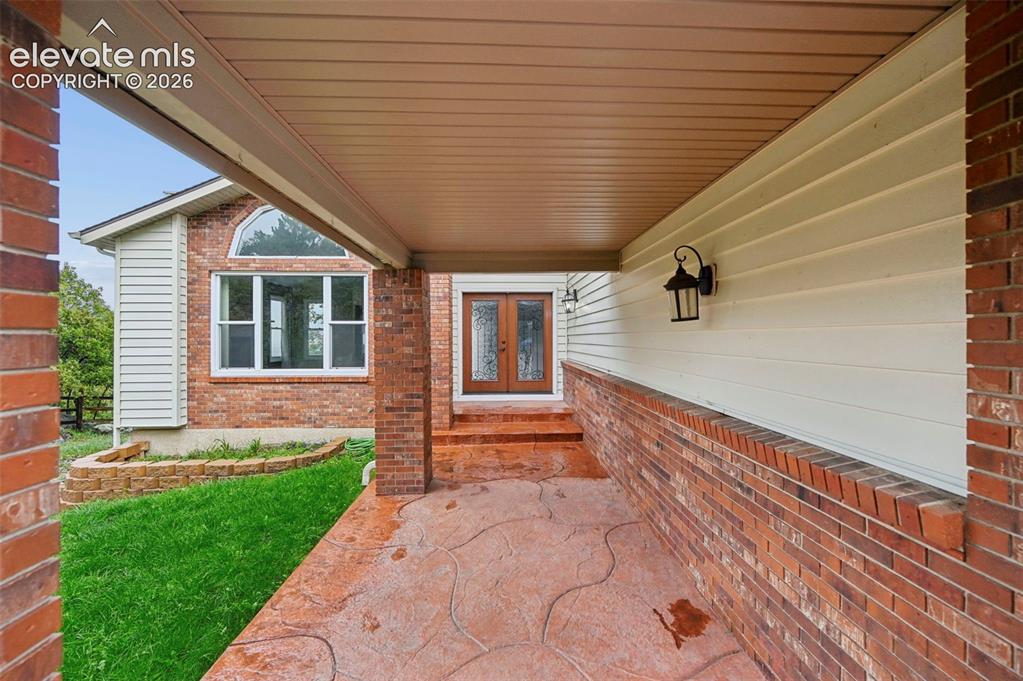 Image 2 of 45: Stamped concrete walkway to the custom wood & iron double doors entry!