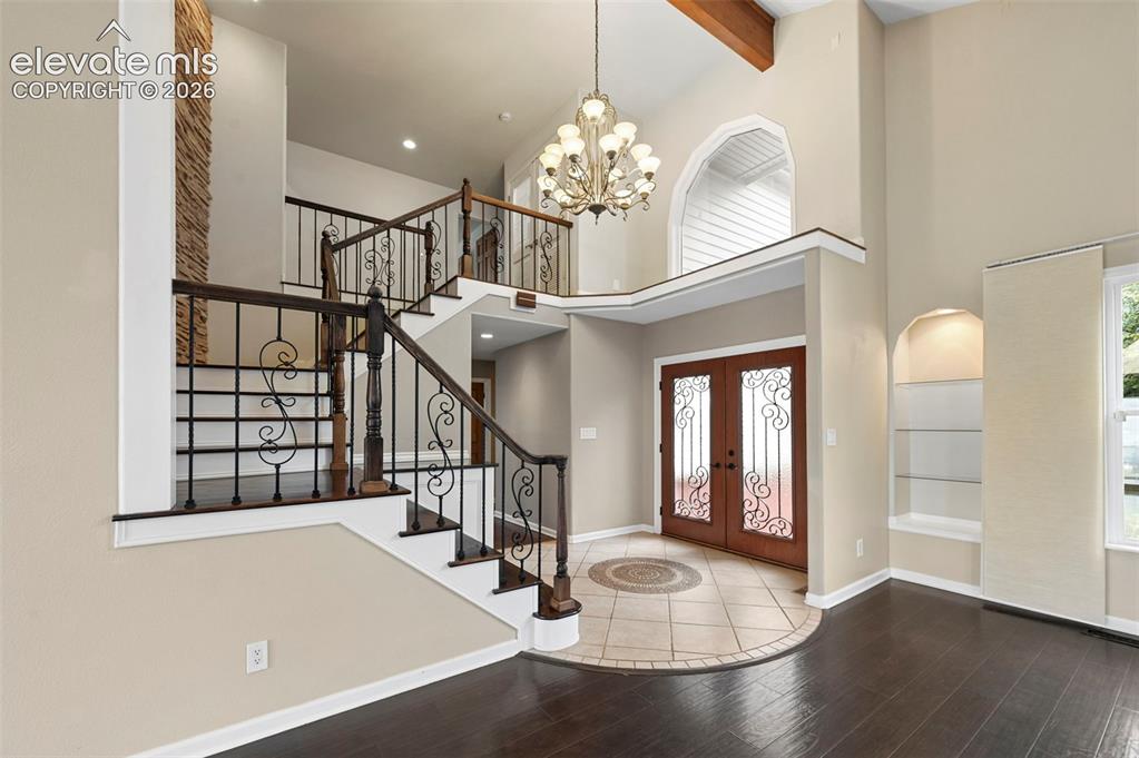 Image 3 of 45: Grand foyer w/ stunning iron staircase and stone wall accent and dramatic c