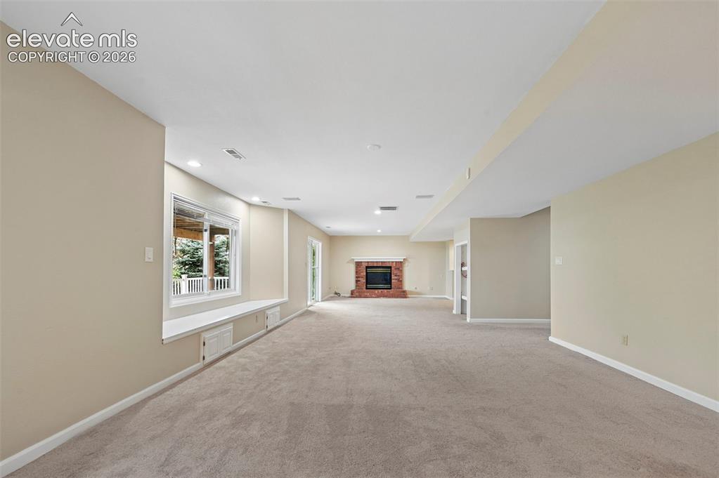 Image 33 of 45: Large walkout basement with brick fireplace,  to lower level deck