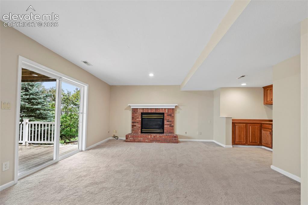 Image 35 of 45: Large walkout basement with brick fireplace to walkout to lower deck 
