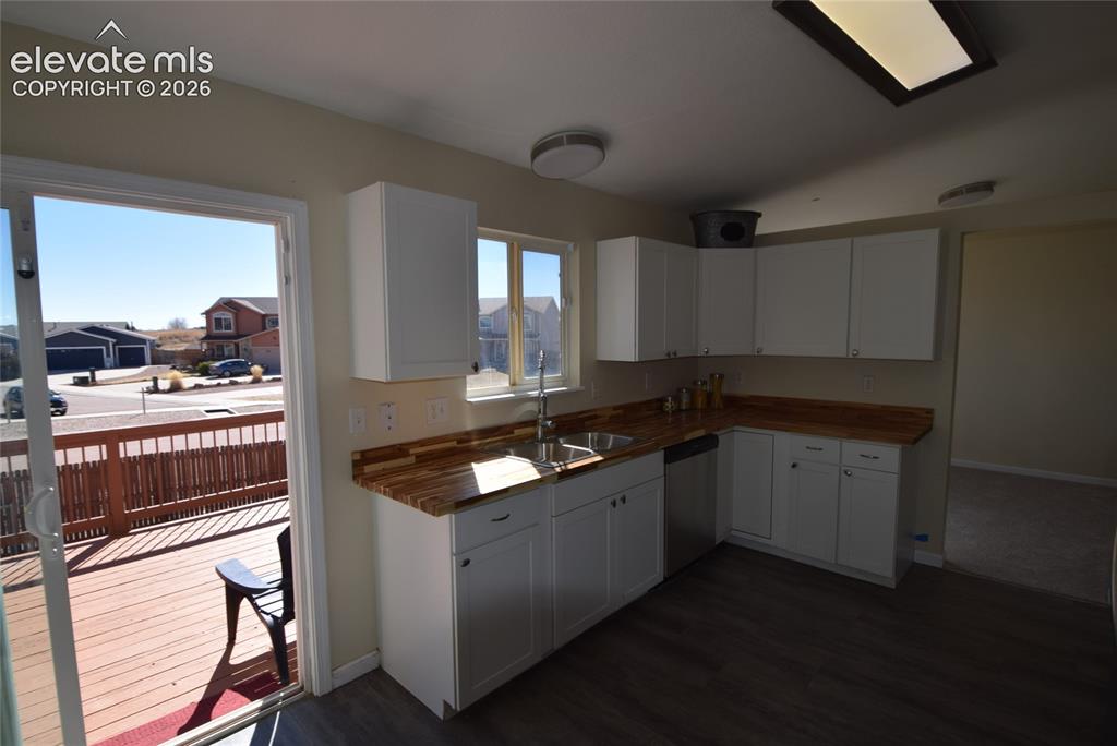 Image 12 of 44: Kitchen featuring L-shaped white cabinetry, wood-finish countertops, and st