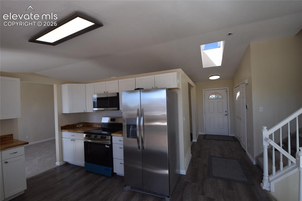 Image 13 of 44: Kitchen featuring white cabinetry, wood-finish countertops, and stainless s