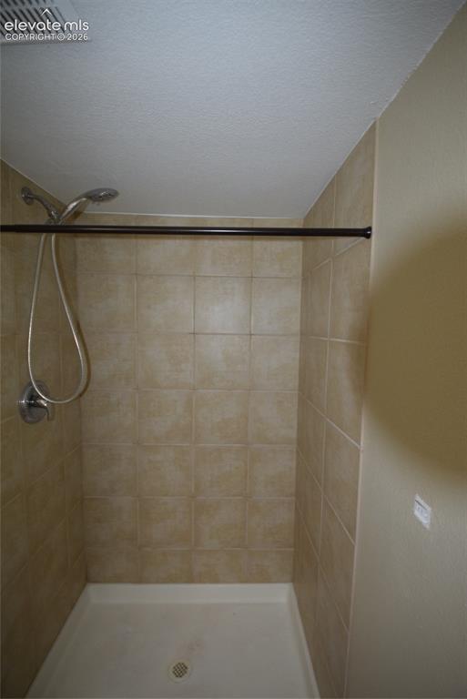 Image 26 of 44: Shower stall featuring neutral-toned square wall tiles, a white shower pan,