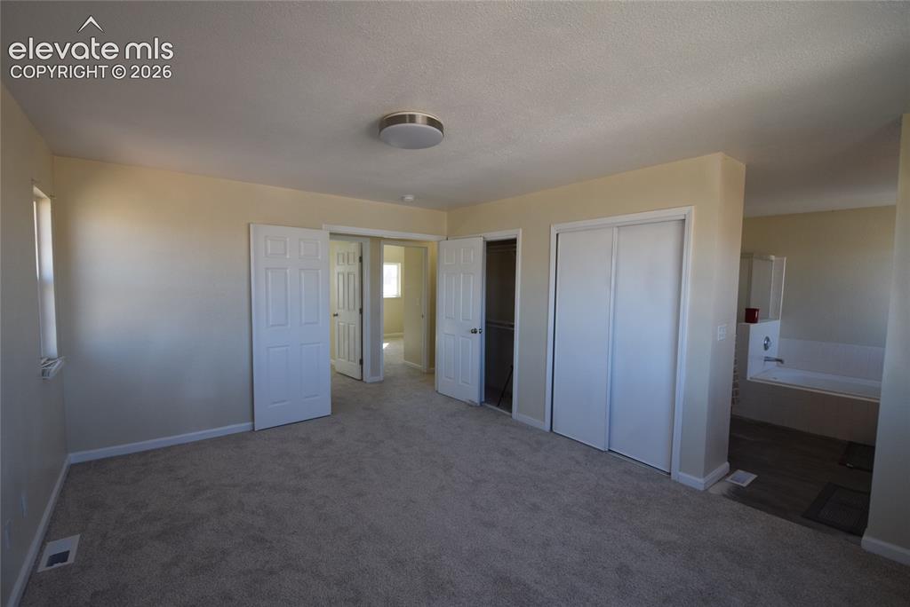 Image 29 of 44: Carpeted room featuring multiple doorways, a window, and a ceiling-mounted