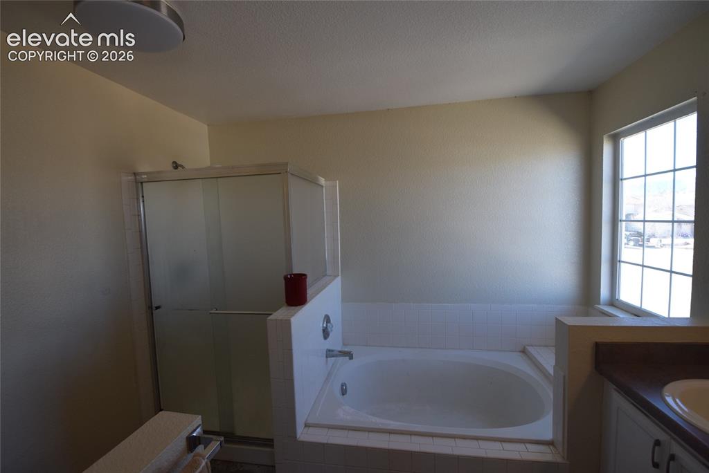 Image 34 of 44: Bathroom featuring a spacious built-in tub, separate glass-enclosed shower,