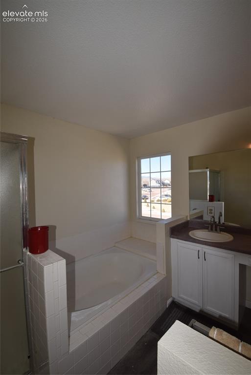 Image 35 of 44: Bathroom featuring a built-in soaking tub with white tile surround, a singl