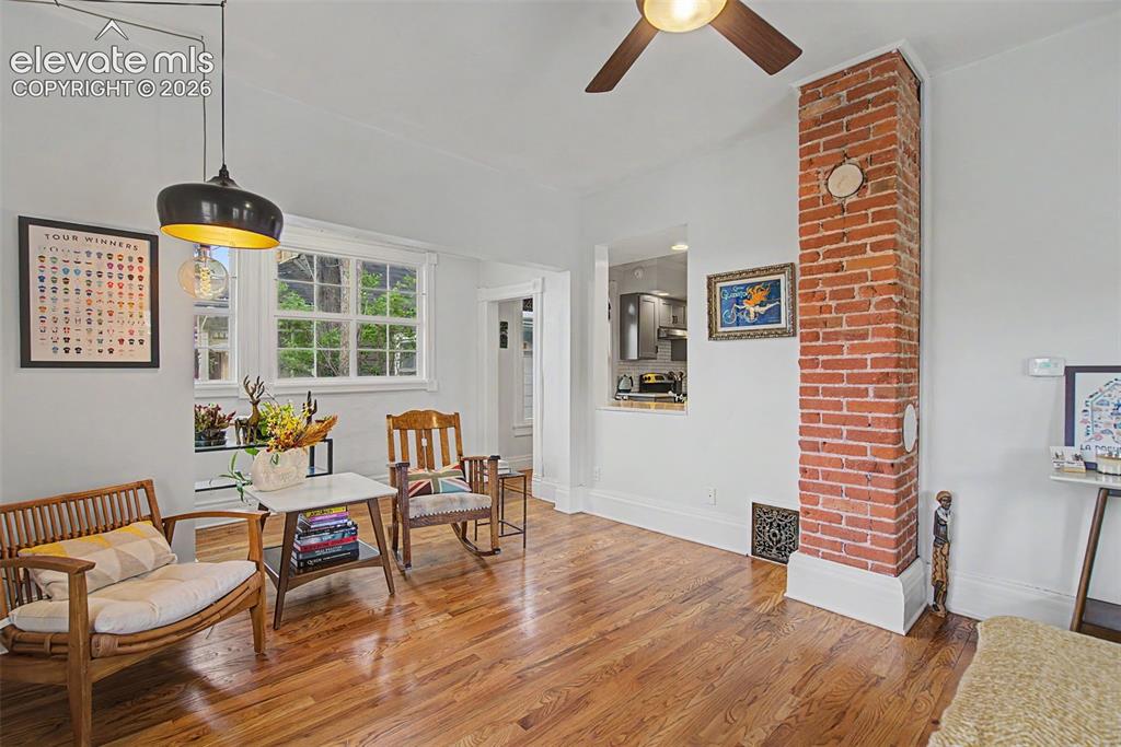 Image 15 of 50: Living area featuring hardwood flooring, exposed brick, and natural lightin
