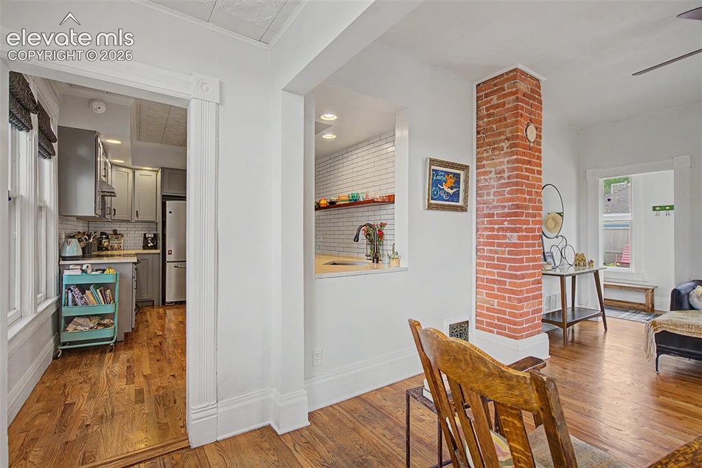 Image 16 of 50: Living area featuring hardwood flooring, exposed brick, natural lighting an