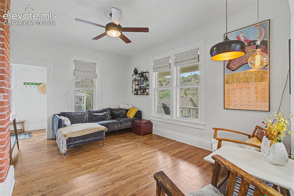 Image 17 of 50: Living area featuring hardwood flooring, exposed brick, and natural lightin