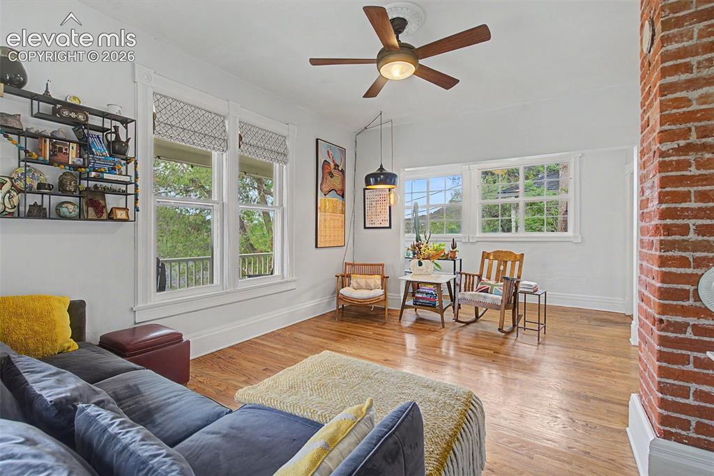 Image 18 of 50: Living area featuring hardwood flooring, exposed brick, and natural lightin