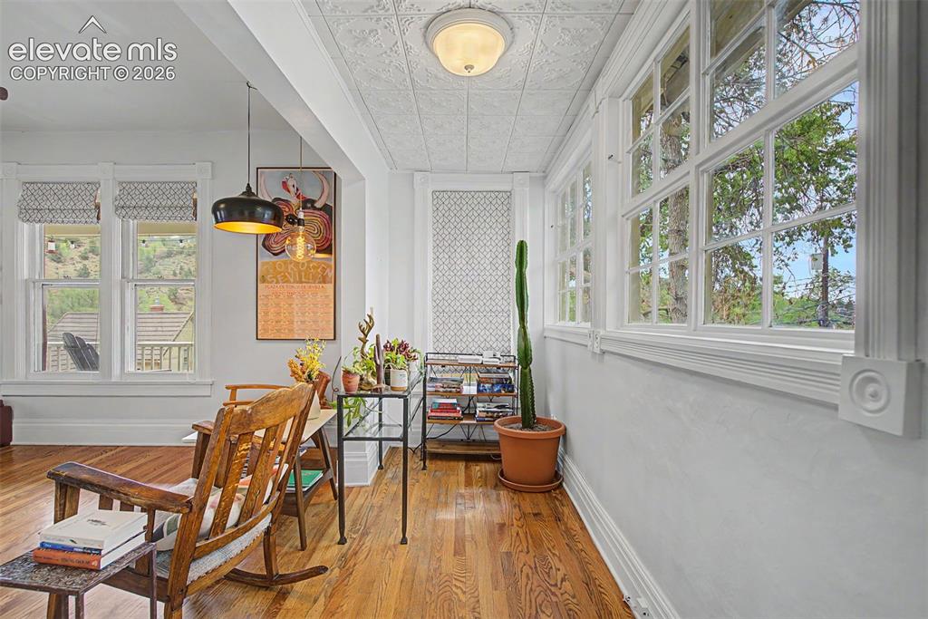 Image 19 of 50: Living area featuring hardwood flooring, exposed brick, and natural lightin