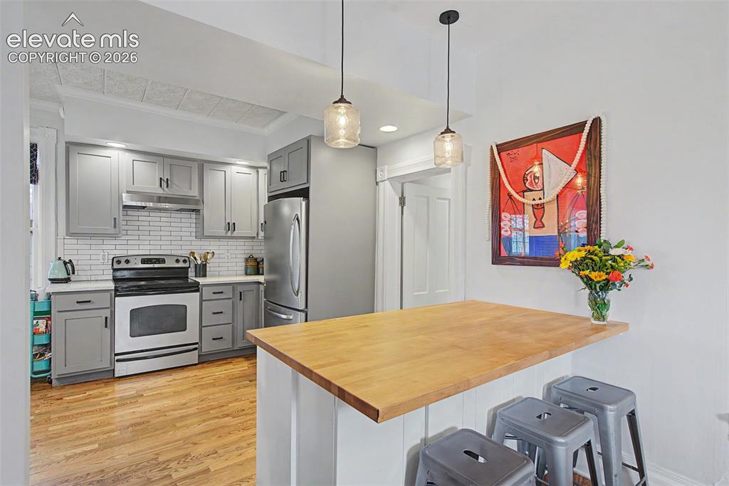 Image 20 of 50: Updated kitchen featuring light gray cabinetry, white tile backsplash, stai