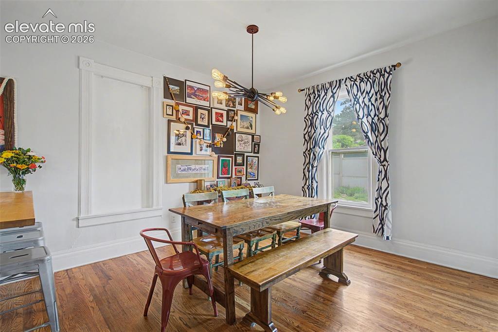 Image 27 of 50: Dining area featuring hardwood flooring throughout and a modern chandelier