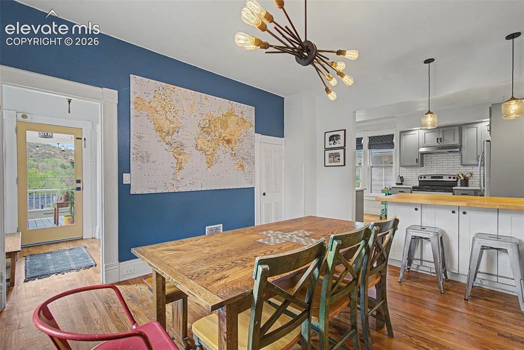 Image 28 of 50: Open-concept dining area featuring hardwood flooring, a modern chandelier,