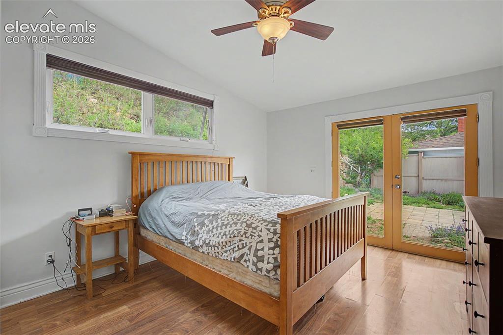 Image 30 of 50: Primary bedroom featuring hardwood flooring and double doors that leads out