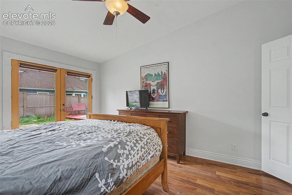 Image 31 of 50: Primary bedroom featuring hardwood flooring and double doors that leads out