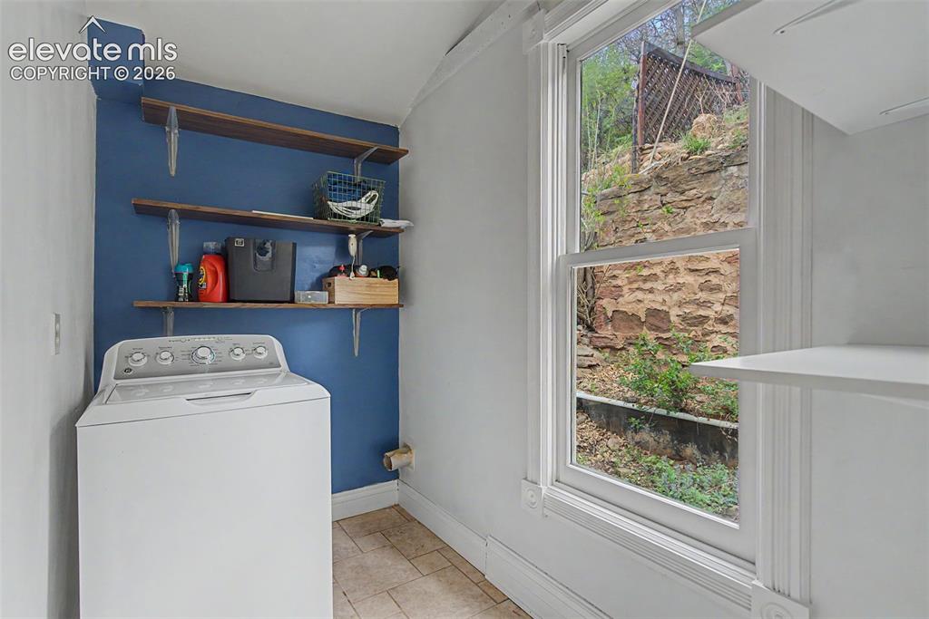 Image 33 of 50: Dedicated laundry space featuring a white top-load washing machine, shelvin