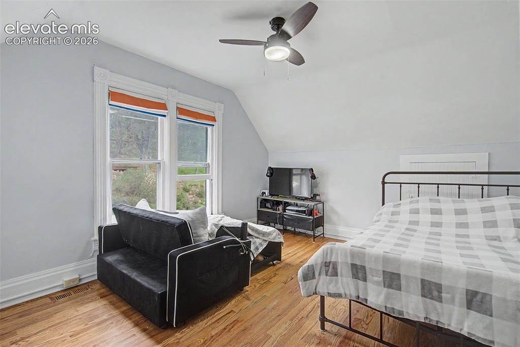 Image 36 of 50: Upper bedroom featuring wood flooring and ceiling fan