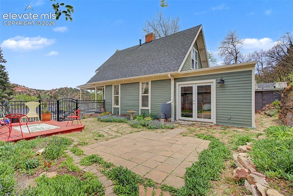 Image 42 of 50: Exterior photo of structure featuring wooden deck, paved patio area, and do