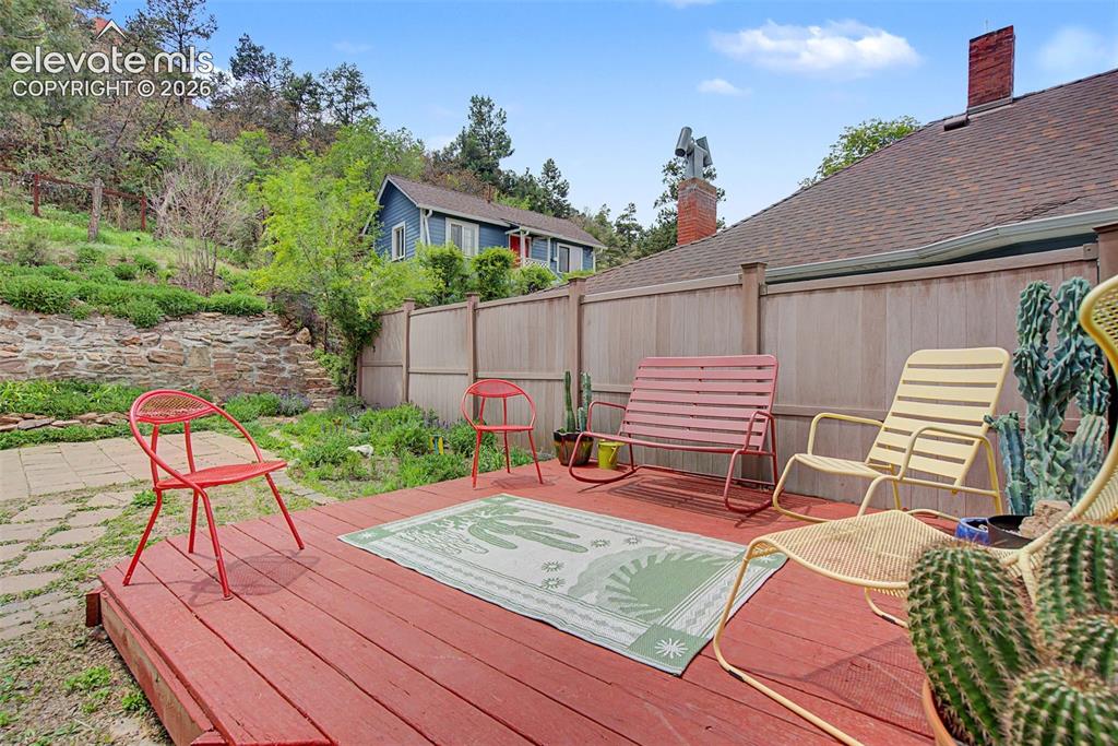 Image 43 of 50: Outdoor wood deck with red finish, surrounded by a wood privacy fence and n