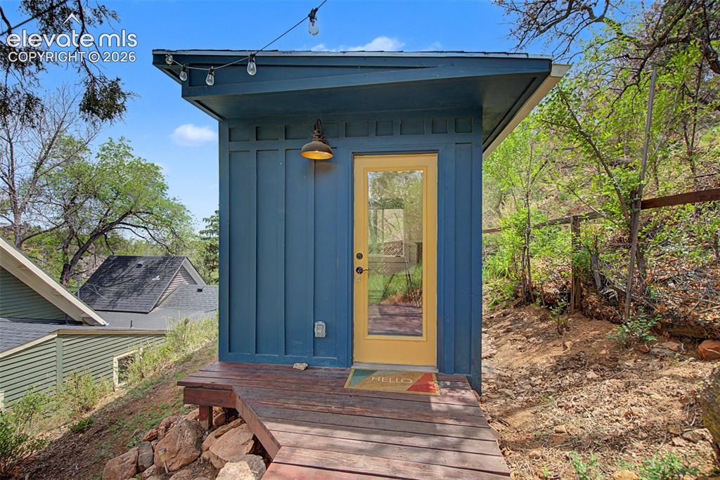 Image 46 of 50: Creative studio entry in backyard with electricity and baseboard heating.