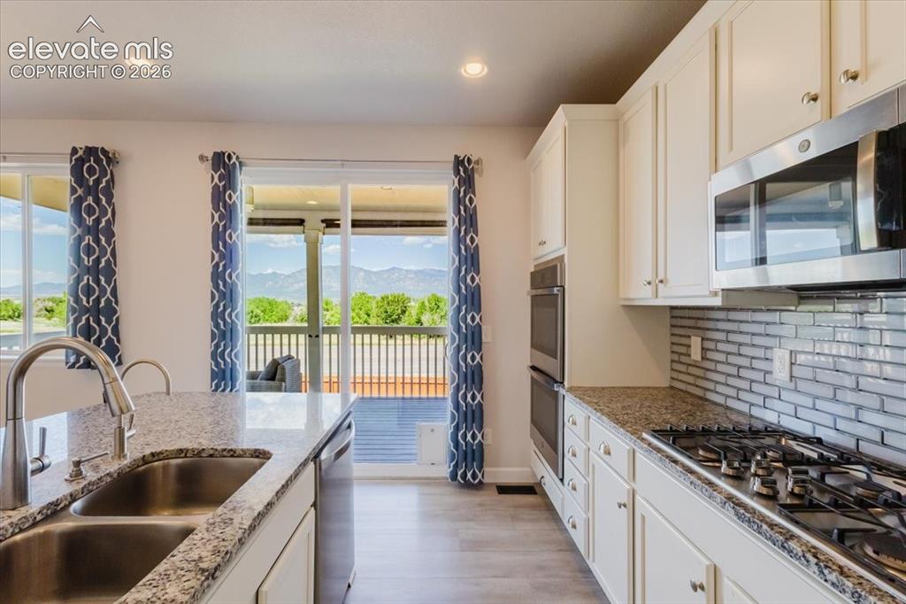 Image 12 of 50: Modern kitchen featuring light cabinetry, stainless steel appliances, grani