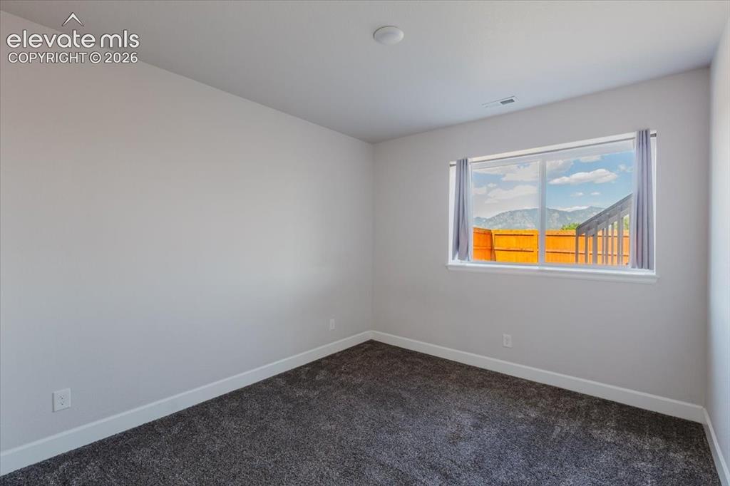 Image 18 of 50: Room with light gray walls, dark gray carpeting, and white baseboards