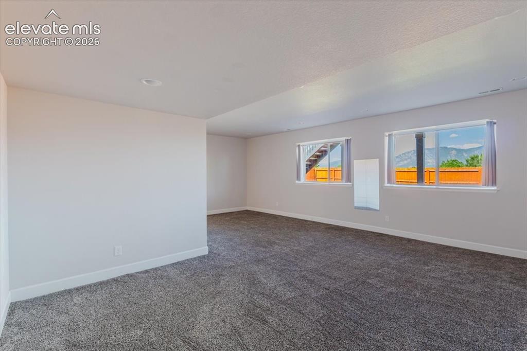 Image 22 of 50: Spacious room featuring neutral-toned walls, recessed lighting, and grey te