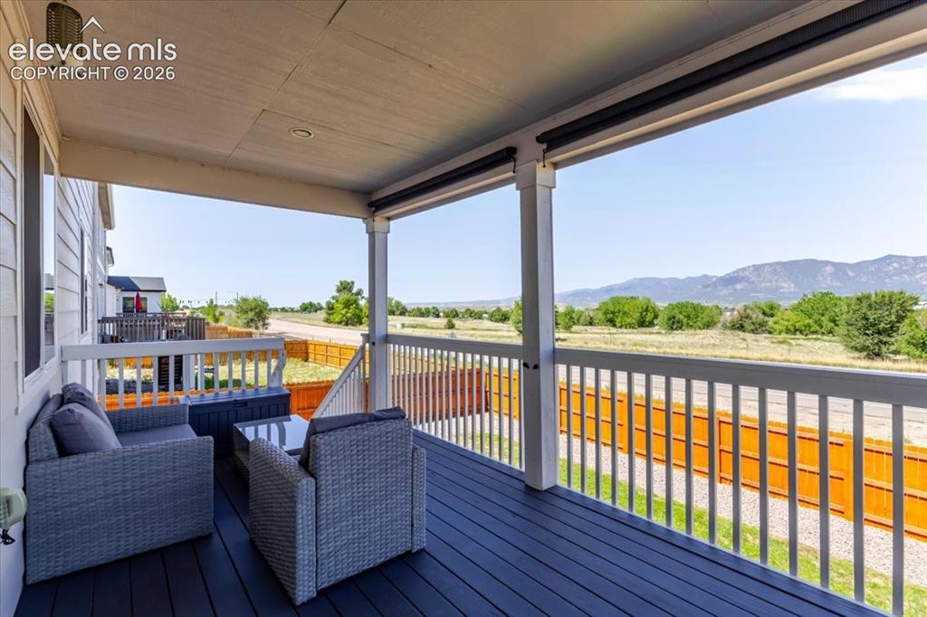 Image 23 of 50: Covered outdoor deck featuring a dark wood-finish floor and white railings