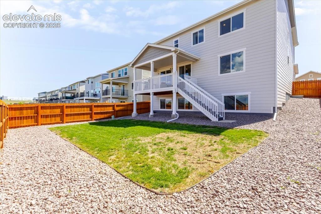 Image 25 of 50: Rear exterior featuring a covered deck with white railings and stairs, a fe