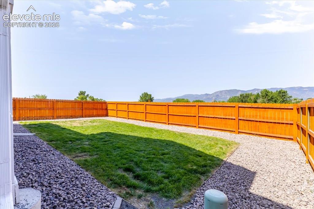 Image 27 of 50: Expansive backyard featuring a manicured lawn, gravel pathways, and a perim