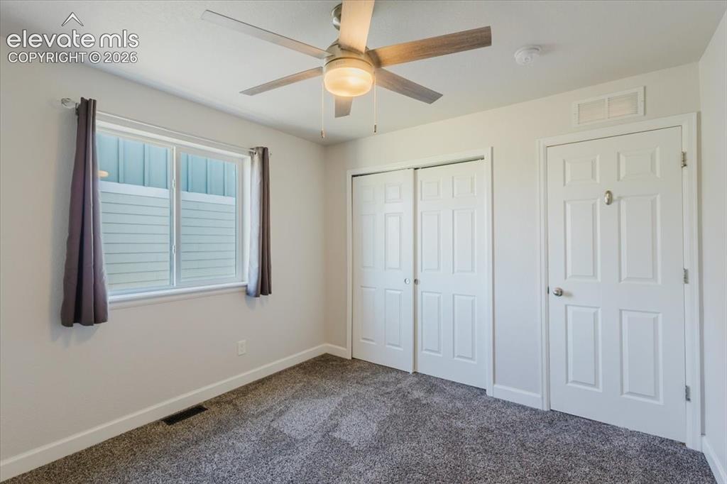 Image 31 of 50: Carpeted room featuring a ceiling fan with integrated lighting, a double-pa
